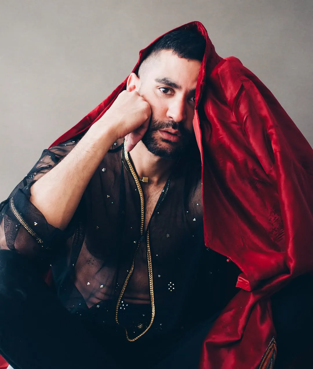 Draped in crimson silk, hand to cheek