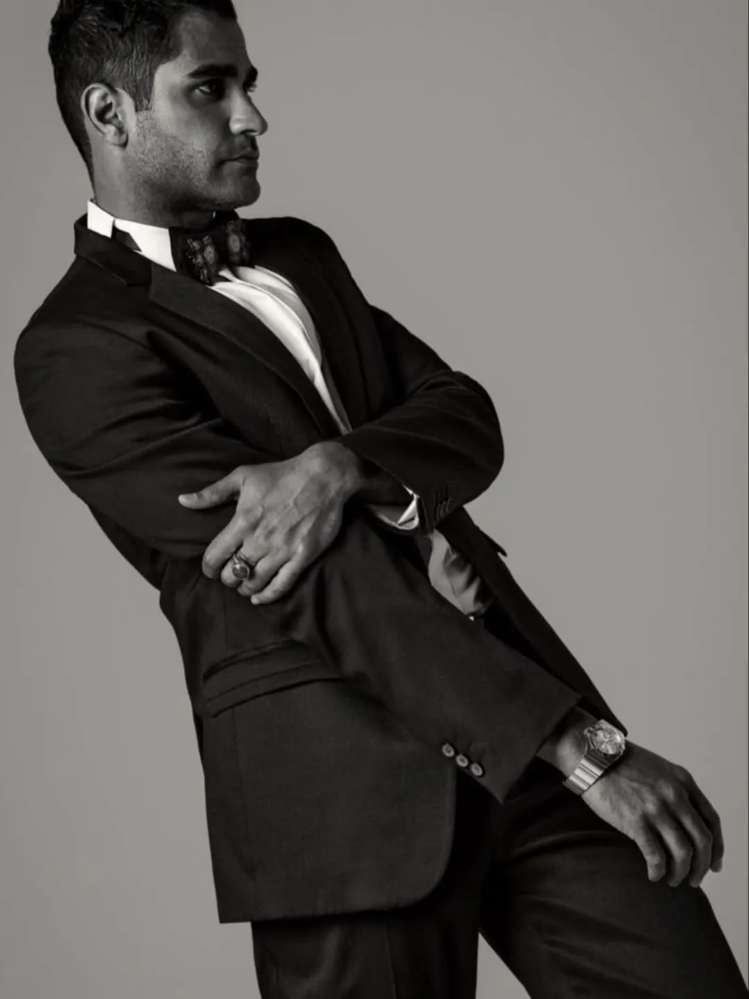 Leaning in a tuxedo against a grey studio wall